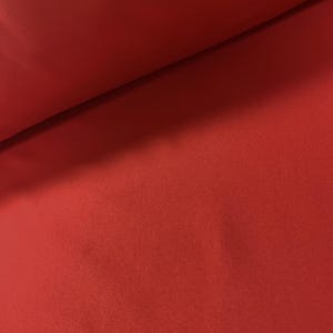 Könnte beinhalten: Nahaufnahme eines einfarbigen roten Stoffes. Der Stoff hat eine weiche, flauschige Textur.