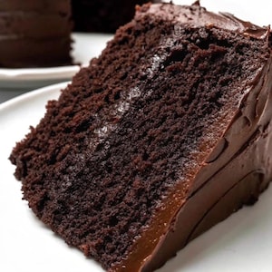 Op de afbeelding: Een plak chocoladetaart met chocolade glazuur. De taart is donkerbruin en het glazuur is glad en glanzend.