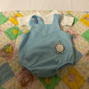 Op de afbeelding: Een lichtblauwe baby romper met een wit onderhemd. De romper heeft een klein geborduurd olifantje op de voorkant.