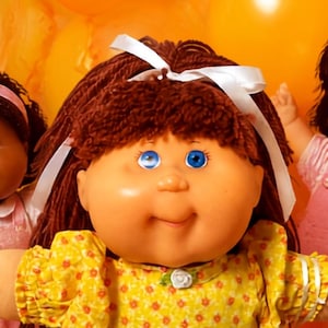 Könnte beinhalten: Eine Gruppe von fünf Cabbage Patch Kids Puppen mit Wollhaaren und Vinylgesichtern in bunten Outfits, umgeben von orangefarbenen Luftballons und Lollis. Eine zentrale Puppe trägt ein gelbes Blumenkleid mit weißem Band und weißen Schuhen.
