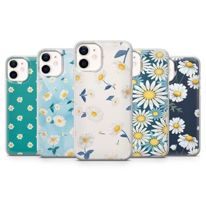 May include: Five phone cases with daisy floral patterns. The cases feature a variety of backgrounds, including teal, light blue, white, and navy. The daisies have white petals and yellow centers. The cases are designed to fit a smartphone.