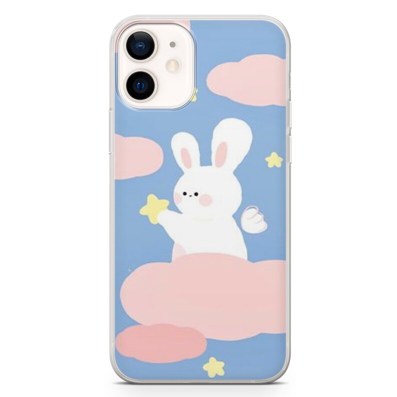 Puede incluir: Una funda transparente para tel&eacute;fono con un conejo blanco sosteniendo una estrella amarilla sobre un fondo azul con nubes rosas y estrellas amarillas.