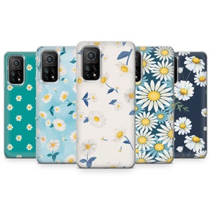 May include: A collection of five phone cases with daisy floral patterns. The cases feature a variety of backgrounds, including teal, light blue, and white. The daisy designs have white petals and yellow centers, with some cases also including blue leaves.