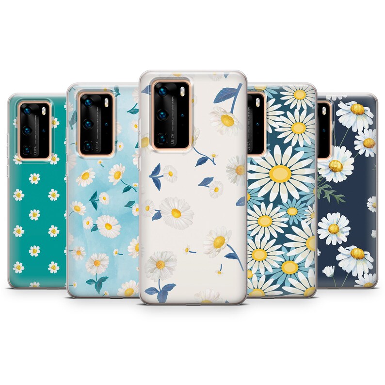 May include: Five phone cases with daisy floral patterns. The cases feature a variety of backgrounds, including teal, light blue, and navy, with white and yellow daisy designs. The cases are made of a clear, protective material.