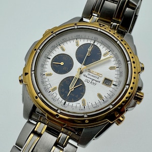 May include: A silver and gold Seiko Quartz Chronograph SQ 100 watch. The watch has a silver face with gold hands and markers, three sub-dials, and a date window. The watch has a stainless steel strap.