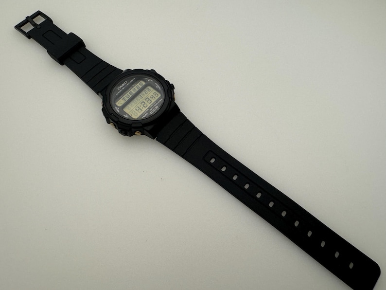 May include: A black digital wristwatch with a black resin band. The watch face displays the time, date, and other functions.