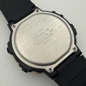 May include: Black Casio wristwatch with a silver back. The back of the watch has the text "CASIO DBW-32 STAINLESS STEEL BACK WATER RESISTANT JAPAN T".