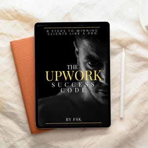 May include: A tablet displaying "The Upwork Success Code" with the tagline "8 Steps to Winning Clients Like a Pro." The cover features a grayscale image of a man's face. An orange notebook and a white stylus are also visible.
