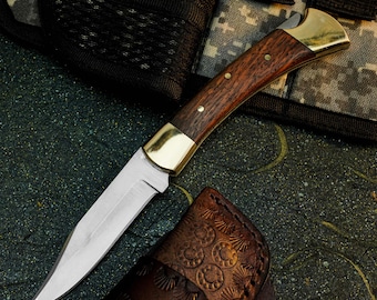 Navaja plegable de acero D2 con mango de madera y funda de cuero.