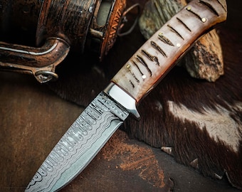Cuchillo de caza de Damasco hecho a mano, con mango de cuerno de carnero y funda de cuero.