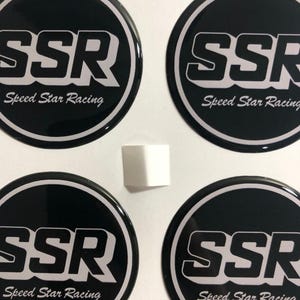 Könnte beinhalten: Vier runde Aufkleber in Schwarz und Silber mit dem Text "SSR Speed Star Racing" in weißen Buchstaben.