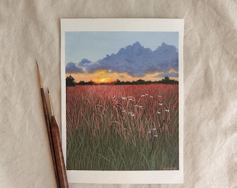May include: A watercolor painting of a sunset over a field of tall grass. The sky transitions from blue to orange, with dark clouds. Two paintbrushes with wooden handles are next to the painting.