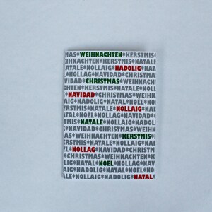 May include: A white card with a repeating pattern of the words "Christmas", "Navidád", "Noël", "Natale", "Weihnáchten", "Kerstmis", "Nollaig", and "Nadólig" in red, green, and black.
