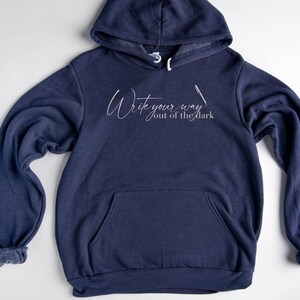 May include: A navy blue hoodie with a white graphic that says "Write your way out of the dark".