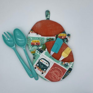 May include: Two teal pot holders with a vintage camper van design. The pot holders have a red and white camper van with the text "Home is Where the WHL is" and "Not All Who Wander Are Lost".