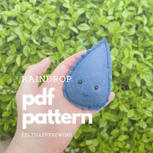 May include: A hand holds a blue felt raindrop with a smiling face. The text "RAINDROP pdf pattern FELTHAPPYSEWING" is below the raindrop.