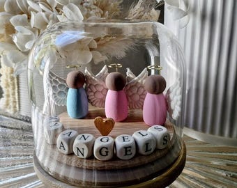 May include: A glass dome with a wooden base containing three small angel figurines with wings. The angels are painted in pink and blue colors. The base has wooden blocks spelling out "My Angels".