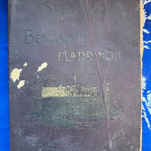 May include: The Speeches of Benjamin Harrison, a dark purple book with gold lettering and a gold embossed image of a building with a flag on top.