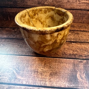May include: A brown and white ceramic bowl with a crackled glaze. The bowl is round and has a wide rim.