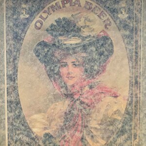 Puede incluir: Anuncio vintage de Olympia Beer con una mujer que lleva un gran sombrero y una bufanda roja. El texto "Olympia Beer" est&aacute; escrito en una fuente decorativa.