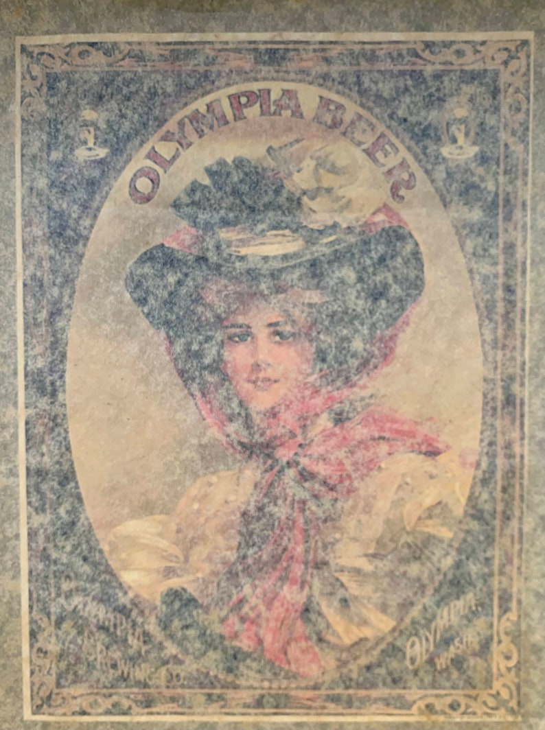Puede incluir: Anuncio vintage de Olympia Beer con una mujer que lleva un gran sombrero y una bufanda roja. El texto "Olympia Beer" est&aacute; escrito en una fuente decorativa.