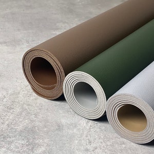 May include: Three rolled up pieces of leather in different colours: brown, green, and grey. The leather is textured and has a natural look.