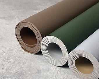 May include: Three rolled up pieces of leather in different colors: brown, green, and gray. The leather is textured and has a natural look.