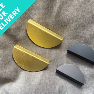 May include: Two gold and two black half-circle cabinet pulls. The pulls are made of metal and have a brushed finish.