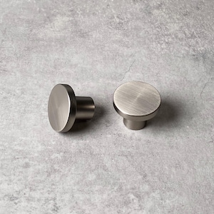 May include: Two silver round cabinet knobs with a brushed finish.