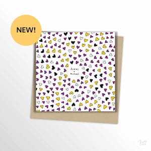 May include: A greeting card with a white background covered in black, yellow, purple, and white heart shapes. The card has the text "Andres + Michael" and is labeled "NEW!" with a yellow circle.