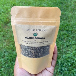 May include: A brown paper pouch with a label that reads "ANCIENT HERBS CO. USBA BLACK COHOSH 1 oz Packaged by Ancient Herbs Co Orange, Texas USA WWW.ANCIENTHERRSCO.COM". The pouch contains dried herbs.