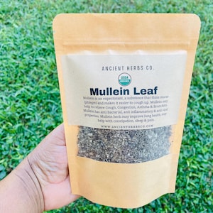 May include: A brown paper bag with a white label that reads "Ancient Herbs Co. USDA Organic Mullein Leaf". The label describes the benefits of Mullein Leaf, including its use as an expectorant, and its potential to help with cough, congestion, asthma, bronchitis, and other respiratory issues. The bag contains dried Mullein Leaf.