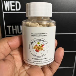 May include: A white bottle with a black label that says "ANCIENT Herbs Co." and "Ashwagandha". The bottle contains 80 capsules of 500mg each. The label also says "Vegan | Wildcrafted | Organic | Non GMO".