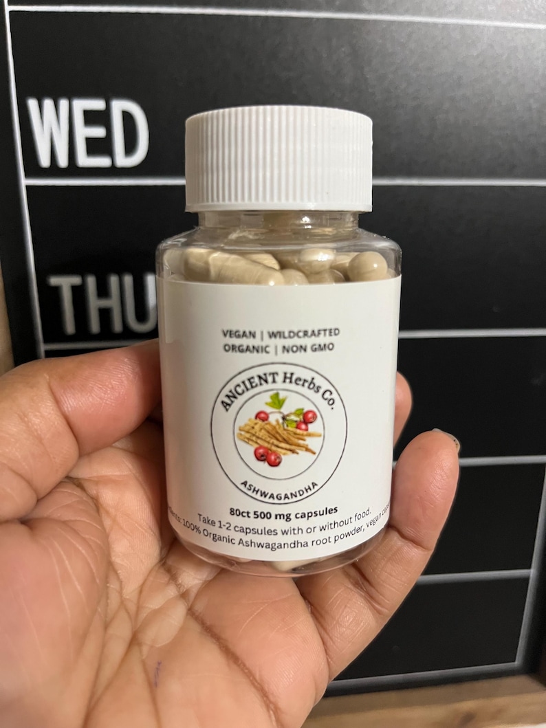 May include: A white bottle with a black label that says "ANCIENT Herbs Co." and "Ashwagandha". The bottle contains 80 capsules of 500mg each. The label also says "Vegan | Wildcrafted | Organic | Non GMO".