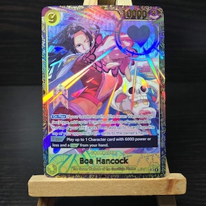 May include: A holographic trading card featuring Boa Hancock from the Seven Warlords of the Sea/Kuja Pirates. The card has a 10000 power rating and includes game text. The artwork depicts Boa Hancock in a dynamic pose with a skull and heart design.