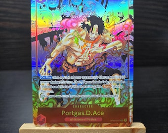 May include: A holographic trading card featuring the character Portgas D. Ace from the "Whitebeard Pirates" series. The card has a vibrant, colorful design with the number 7 and the text "7000" prominently displayed. The card is on a small wooden easel.