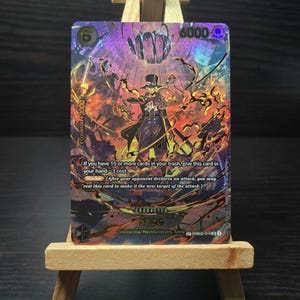 May include: A holographic trading card featuring the character Sabo from the Dressrosa/Revolutionary Army. The card has a purple and orange background with the text "COUNTER+2000" and "6000". The card also includes game instructions.