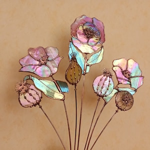 K&ouml;nnte beinhalten: Eine dekorative Glasblumenanordnung mit Kupferstielen. Die Blumen zeigen Schattierungen von Rosa, Lila und Gr&uuml;n mit irisierenden Eigenschaften. Das Design umfasst detaillierte Samenkapseln und Bl&uuml;tenbl&auml;tter.