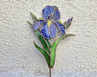 May include: A stained glass iris flower garden stake. The flower has blue and purple petals with yellow accents, green leaves, and a copper-coloured stem. The glass is outlined with copper-coloured metal.