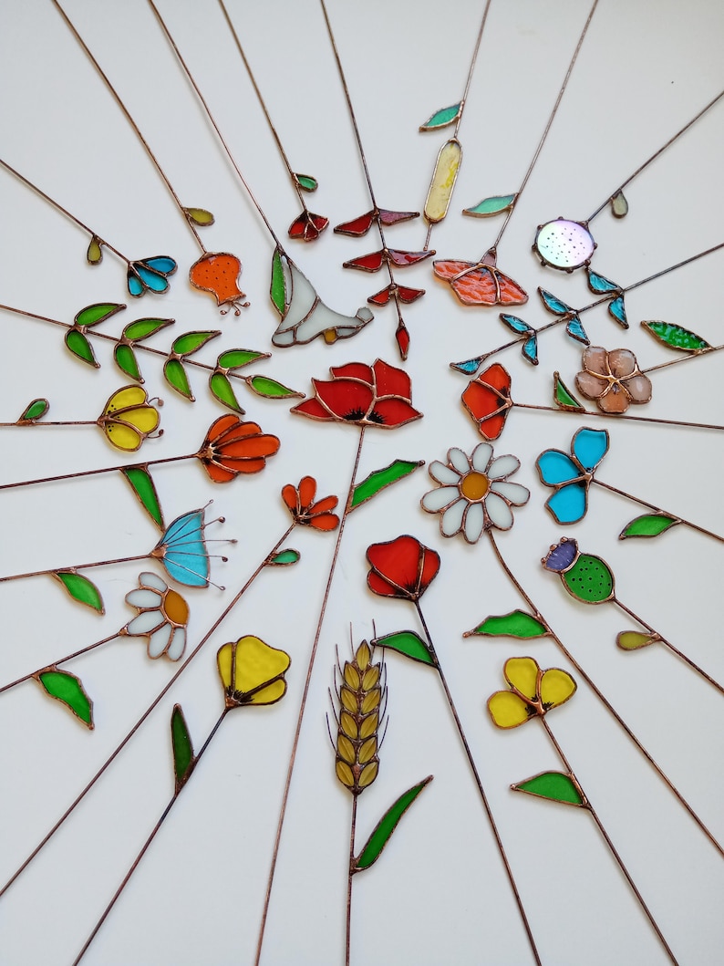 May include: A collection of colorful stained glass flowers and leaves with copper stems arranged in a radial pattern. The flowers include red poppies, yellow tulips, and blue daisies. The glass has various textures and colors.