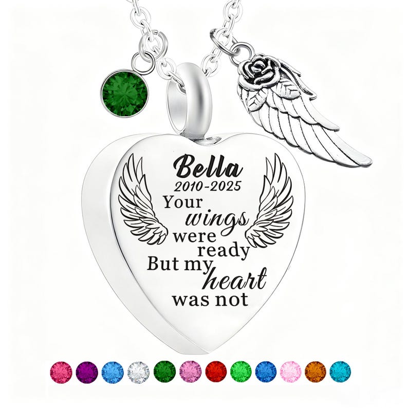 May include: A silver heart-shaped pendant necklace with the inscription "Bella 2010-2025 Your wings were ready But my heart was not." The necklace includes a green gemstone and a rose with a wing charm.