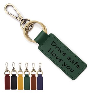 May include: Green leather keychain with a gold metal key ring and a split ring. The keychain has the text "Drive safe I love you" engraved on it. The keychain is shown with six other keychains in different colors.
