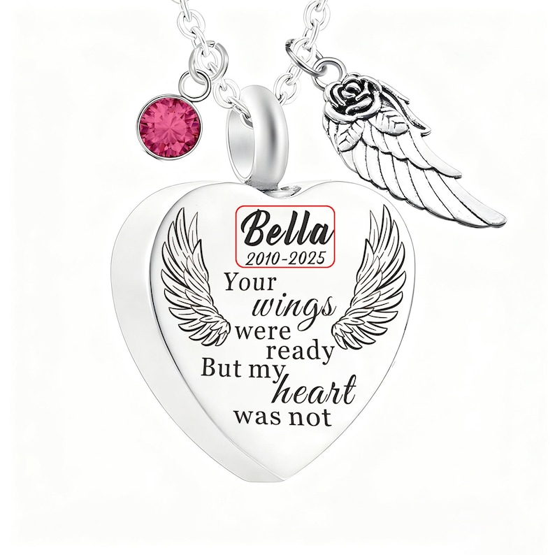 May include: A silver heart-shaped pendant necklace with engraved wings and the text "Your wings were ready but my heart was not." Includes a pink gemstone and a rose with a wing charm. The name "Bella" and dates 2010-2025 are also visible.