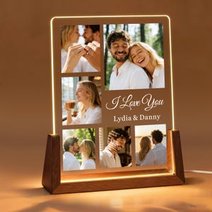 May include: A personalized photo lamp with a wooden base and a rectangular light panel. The panel displays six photos and the text "I Love You" with the names "Lydia & Danny". The lamp emits a warm, soft glow.