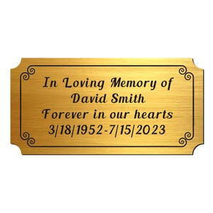 May include: Gold-colored metal plaque with the text "In Loving Memory of David Smith Forever in our hearts 3/18/1952-7/15/2023".