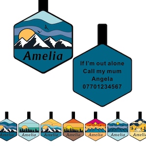 May include: Set of eight hexagonal-shaped personalized name tags with a mountain landscape design. The tags feature a blue, yellow, and white color scheme. The text on the tags reads "Amelia". One tag has additional text that reads "If I'm out alone Call my mum Angela 07701234567".