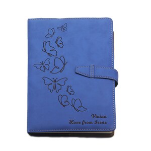 Peut inclure: Un carnet en cuir bleu avec un motif de papillon et le texte "Vivian Love from Irene" grav&eacute; sur le devant.