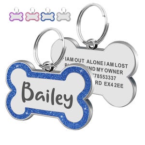 Op de afbeelding: Hondenpenning in de vorm van een bot met de naam "Bailey" in grijze letters. De penning heeft een zilveren rand met blauwe glitteraccenten. De achterkant van de penning bevat contactgegevens.