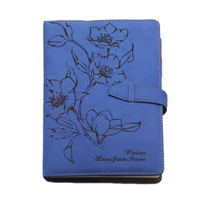 Peut inclure: Un carnet en cuir bleu avec un motif floral et le texte "Vivian Love from Irene" grav&eacute; sur la couverture.