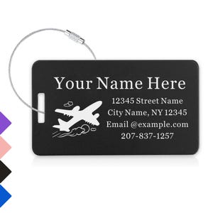 May include: Black luggage tag with a silver wire loop. The tag features the text "Your Name Here", an airplane graphic, and contact information including an email address and phone number.